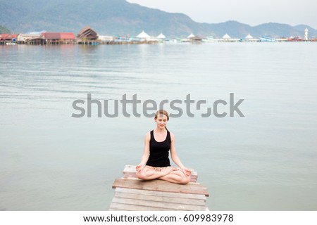 Summer yoga session on a pier - Koh Chang Bang Bao fisherman village, Meditation - lotus pose - padma asana. Activity in south east Asia