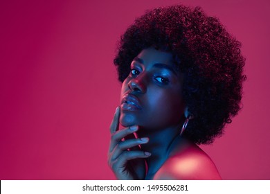 Summer's sunset. Portrait of female fashion model in neon light on gradient background. Beautiful african woman with trendy make-up and well-kept skin. Vivid style, beauty, cosmetics concept.
