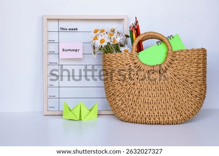 Summer-themed composition featuring a weekly planner, straw bag with daisies, bright notebooks, and colored pencils, symbolizing holidays, vacation, creativity, imagination, and relaxation.