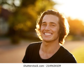 Summertime Always Gets Me Smiling. Portrait Of A Handsome Young Man Standing Outside In The Sun.