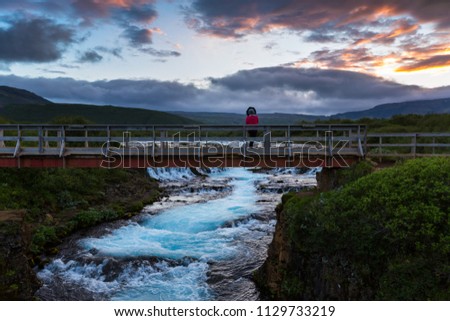 Young man with rucksack crosses a rocky river