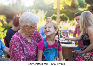 Summertime , a family of three generations having fun around a table in the garden to share a meal. Close-up on a grandmother with her granddaughter in her lap - Powered by Shutterstock