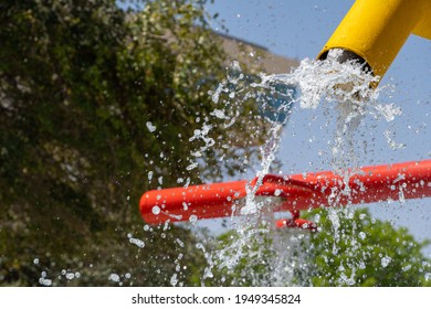 Summertime Fun For The Kids At The Splash Pad To Play With Water Falling From Bright Colored Yellow Fountain To Pool Below.