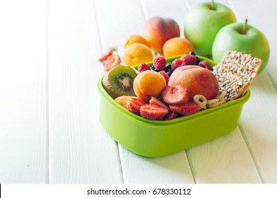 Summertime healthy food concept: Close up of lunch box filled with of fruits, berries and crunches on white wooden background with blank space for text; selective focus - Powered by Shutterstock