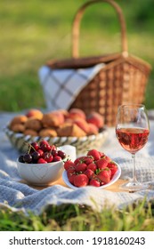 Summertime Healthy Picnic On Nature Background At Sunny Day. Close Up Basket Fruits Strawberries, Cherries, Glass Of Red Wine, On Green Grass In Garden. Summer Weekend Outdoor. Beautiful Still Life