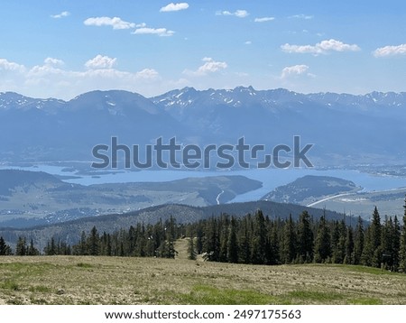 Summertime landscape view looking down at the Dillion Revivor with mountain range and partial cloud covered sky in the background
