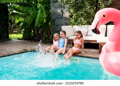 Summertime lifestyle. Girls having fun and relaxing by swimming pool. Kids sitting at poolside and splashing water with legs on sunny day. Summer outdoors activity for children concept - Powered by Shutterstock