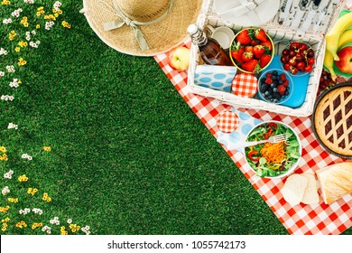 Summertime picnic setting on the grass with open picnic basket, fruit, salad and cherry pie