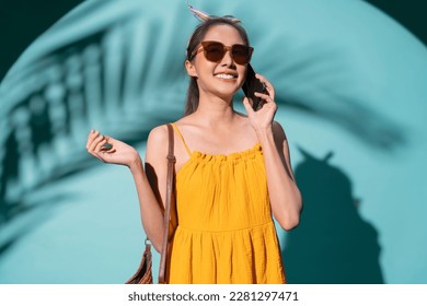 summertime pleasure asia female woman in summer yellow dress wear sun glasses hand using smartphone text conversation with cheerful enjoy summer vacation trip studio shot on colour background  - Shutterstock ID 2281297471