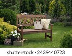 summertime relax in cottage garden. Wooden bench with pillow, lantern and petunia in flowerpot. 