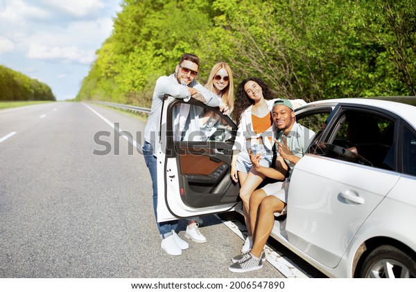 Summertime road trip, traveling with friends,\
joyful vacation concept. Group of diverse young people posing near\
their car on highway, having summer journey, enjoying fun\
adventure, copy\
space