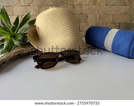 Summery composition with travel elements - Straw hat, sunglasses, and blue beach towel on a white background