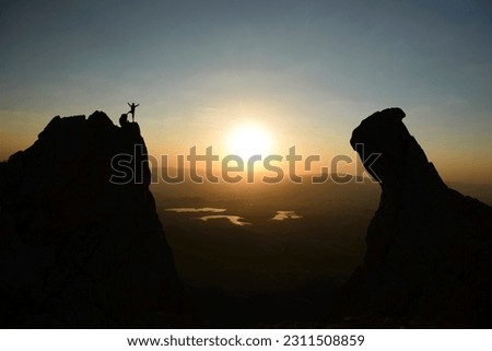 summit activity of mountaineer on jagged cliffs at sunrise