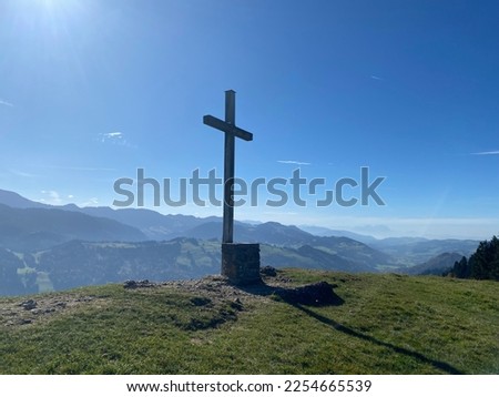 Summit cross in front of mountain panorama with blue sky and sunshine