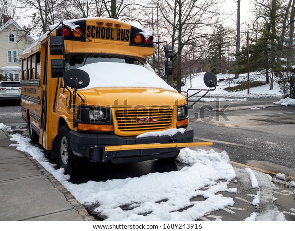 Summit, NJ / USA -\
04/02/2018: yellow school bus parked in snowy parking lot in early\
April in North America