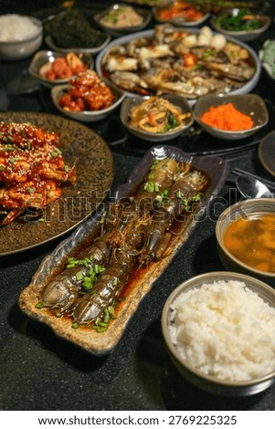 A sumptuous array of Korean dishes is elegantly arranged on a dark tabletop. The spread features a variety of flavors, colors, and textures, ideal for food blogs, restaurant promotions, or culinary guides.