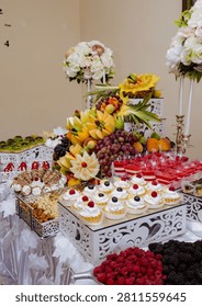 Sumptuous festive table laden with elegant chocolate cakes, sweet berry meringues, and a towering pyramid of vibrant fresh fruit