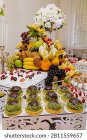 Sumptuous festive table laden with elegant chocolate cakes, sweet berry meringues, and a towering pyramid of vibrant fresh fruit