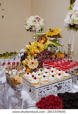 Sumptuous festive table laden with elegant chocolate cakes, sweet berry meringues, and a towering pyramid of vibrant fresh fruit