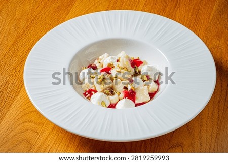 A sumptuous plate of gnocchi sits elegantly, adorned with mozzarella and bright raspberry sauce.