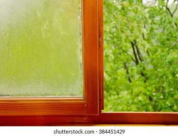 Sun After The First Spring Rain (half-open Old Wooden Window With Raindrops And Out-of-focus Green Trees)