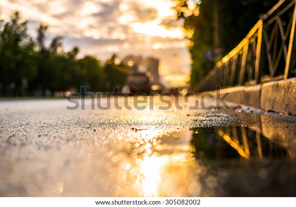 Sun after the rain in the city,\
view of the cars with a level of puddles on the\
pavement