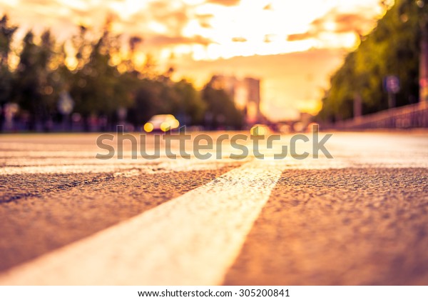 Sun after the rain in the city, view of the\
approaching car with the level dividing line. Image in the\
yellow-purple toning