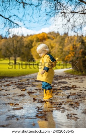 Similar – Image, Stock Photo Sun always shines after the rain. Small bond infant boy wearing yellow rubber boots and yellow waterproof raincoat walking in puddles in city park on sunny rainy day.