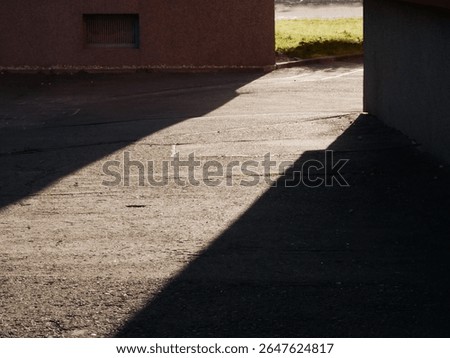 sun beam between the shadow of two buildings marking a gateway on the road surface