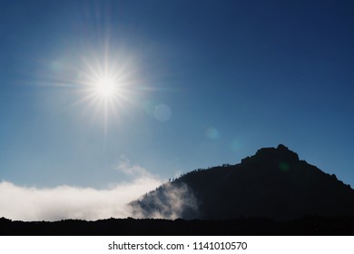 Sun with sun beams and mountain in the clouds