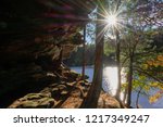 Sun beams sparkling on lake and shining through trees along sandstone bluff