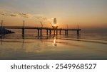 The sun beams through the tower of Brant Street Pier, as it rises over the lake during the morning at Burlington, Ontario, Canada