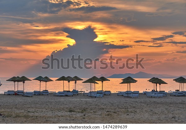 Sun beds, umbrellas and strange black\
clouds at beautiful sunset. Landscape panorama photo was taken in\
July in summer at Enez Beach, Edirne,\
Turkey.