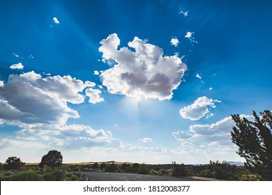 Sun behind clouds with blue sky and road