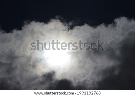 Sun behind the clouds that makes a darker sky. 