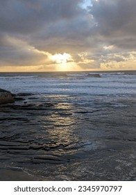 Sun breaking through clouds on over ocean on coast