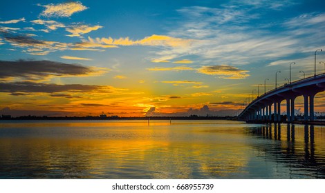 The sun breaking through the clouds on the horizon of the Indian River lagoon in Florida with a bridge