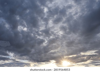 Sun breaking through dark clouds over Lake Mjøsa in Hamar, Norway during dramatic evening sky