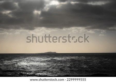 The sun breaks through threatening clouds above the Isle of May