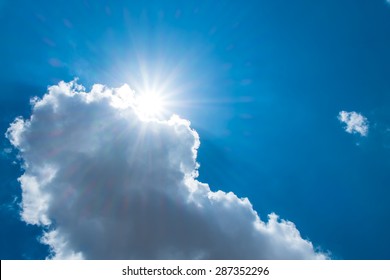 Sun burst behind cloud with dark blue sky