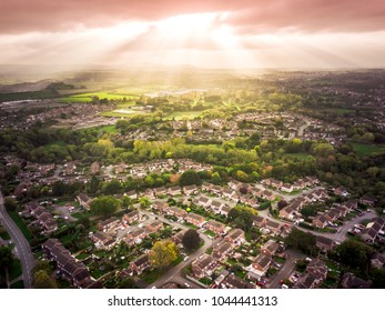 Sun bursting through clouds over traditional British houses with countryside in the background. Dramatic lighting and warm colours to give a homely effect. - Powered by Shutterstock