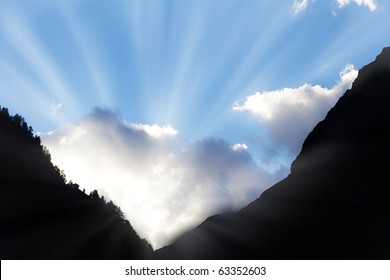 sun bursts through clouds from a dark mountain valley symbol for hope,call not to give up,light at the end of the tunnel