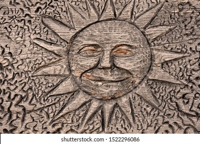 Sun carved on a wooden background stock images. Carved wooden background with sunny symbol. Wooden happy sun. Decorative sun on a natural surface. Wooden sun with face stock images