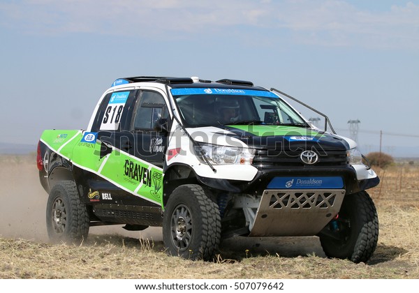 Sun\
City, South Africa - OCTOBER 1, 2016: Close-up view of Speeding\
green and white Toyota Hilux twin cab rally car in race at Sun City\
450 Rally Racing event, Sun City, South Africa \
