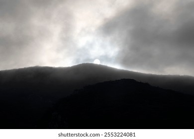sun in the clouds over the mountain