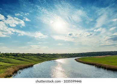 sun in clouds at sunset time over river