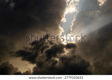The sun comes out from behind the clouds in the blue sky.