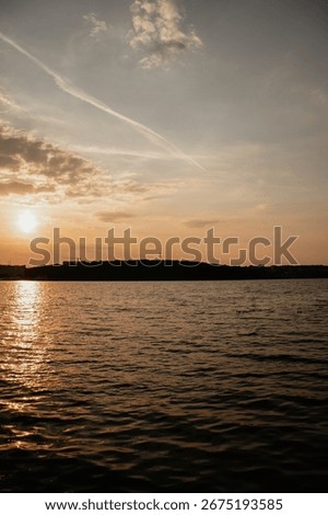 The sun dips below the horizon, casting a warm golden glow over the rippling water. The last light of day creates a beautiful and tranquil scene.