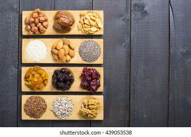 Sun Dried Organic Fruits, Nuts And Oil Seeds On Bamboo Serving Tray, Black Wooden Table Background