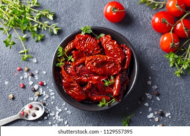 Sun dried tomatoes with fresh herbs and spices. Slate background. Top view.